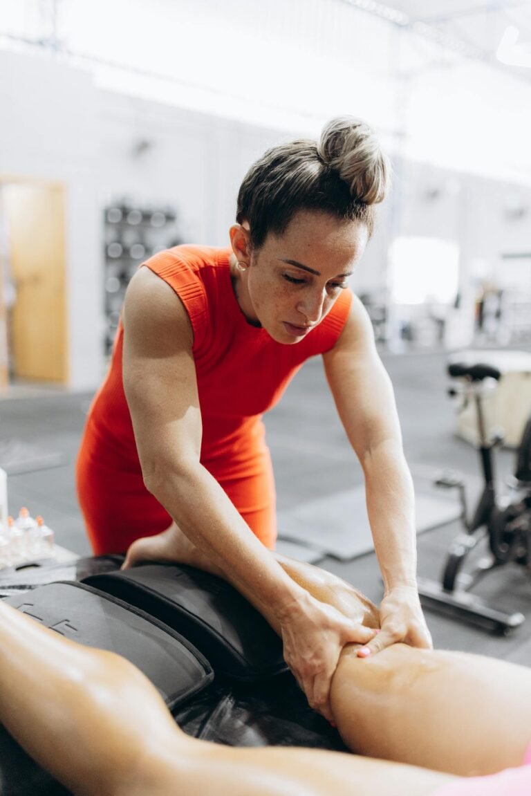 A therapist in red performs myofascial release on a client in a gym setting, enhancing recovery.